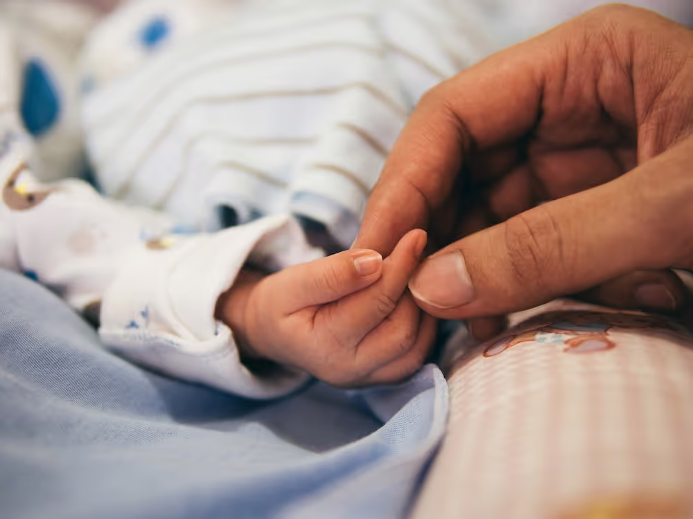 A parent holding their child's hand