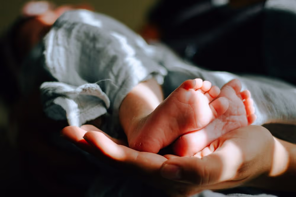 A parent holding their child's feet